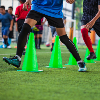 taticas-de-bola-de-futebol-no-campo-de-grama-com-cone-para-treinar-habilidades-de-corrida-de-criancas-na-academia-de-futebol 1